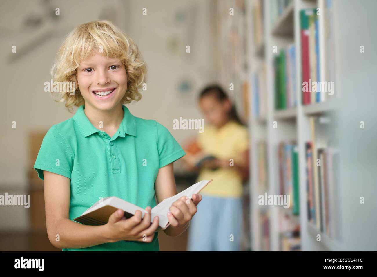 Un écolier joyeux pose pour la caméra à la bibliothèque Banque D'Images