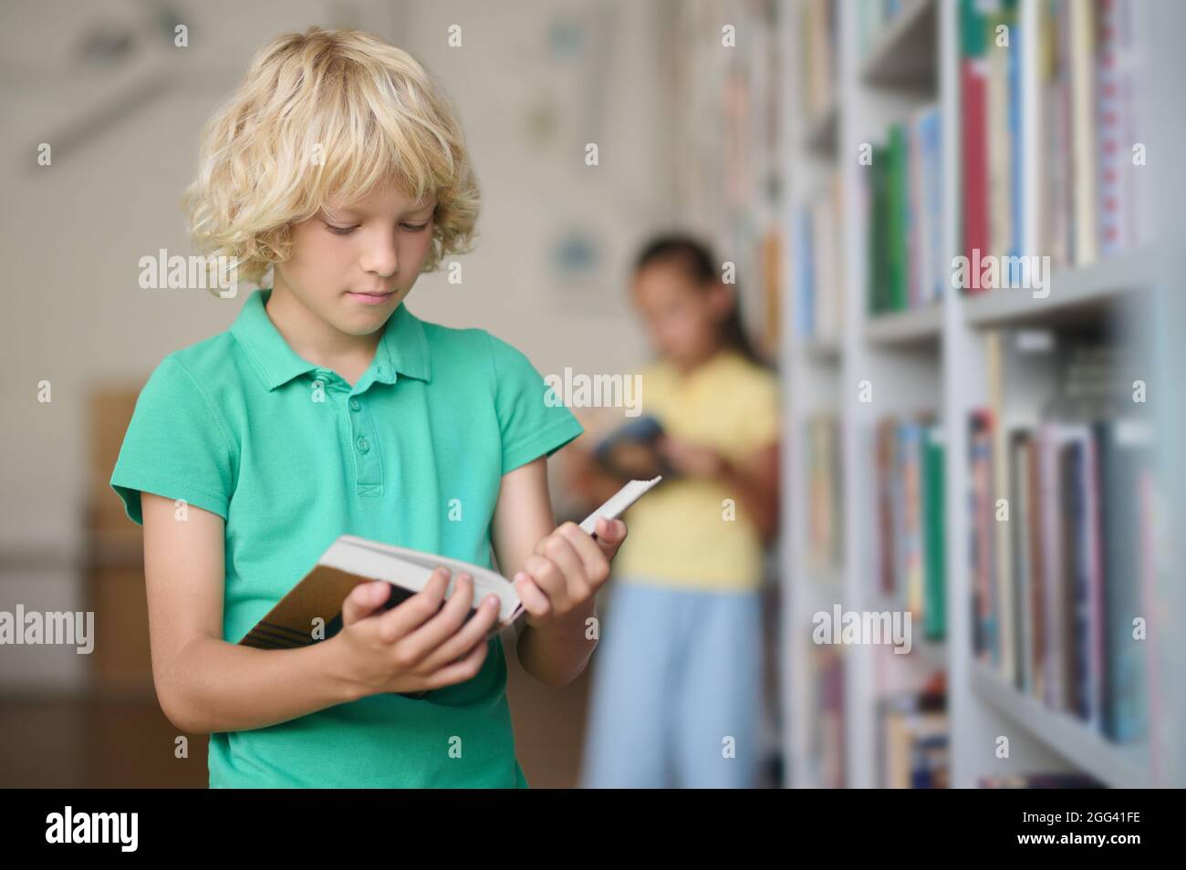 Un garçon sérieux lisant un manuel dans ses mains Banque D'Images