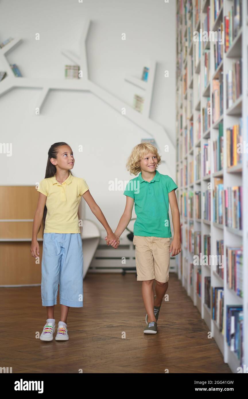Deux enfants impressionnés par une variété de livres sur les étagères Banque D'Images