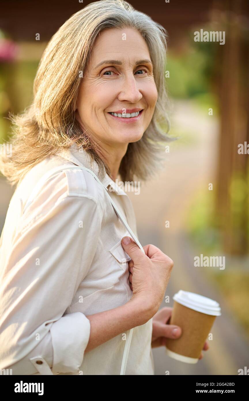 Femme optimiste adulte avec café à l'extérieur Banque D'Images
