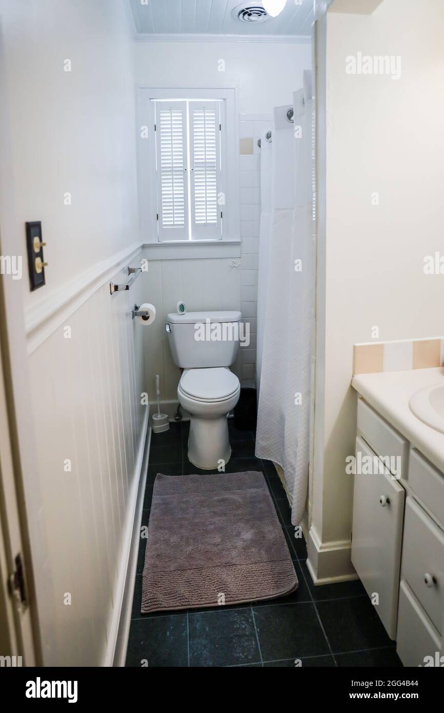 Lavabo blanc de salle de bains avec carreaux vintage, et toilettes dans la salle de bains d'invités de vieux cottage Banque D'Images