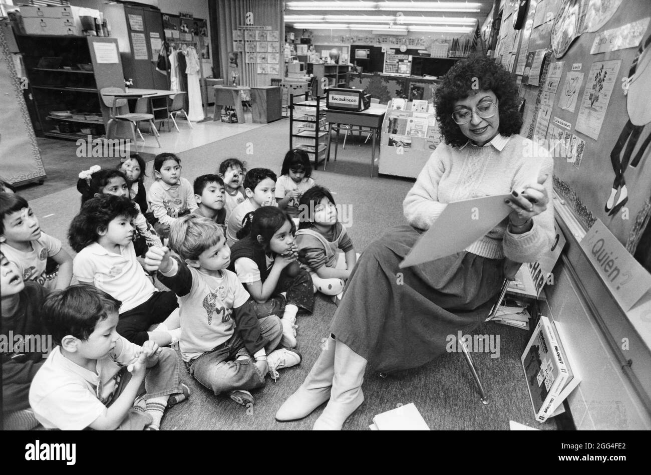 Austin Texas USA, vers 1991: Une enseignante de maternelle hispanique lit aux étudiants hispaniques assis sur le plancher devant elle dans une salle de classe bilingue à l'école élémentaire Sanchez. ©Bob Daemmrich Banque D'Images Austin Texas USA, vers 1991: Une enseignante de maternelle hispanique lit aux étudiants hispaniques assis sur le plancher devant elle dans une salle de classe bilingue à l'école élémentaire Sanchez. ©Bob Daemmrich Banque D'Images