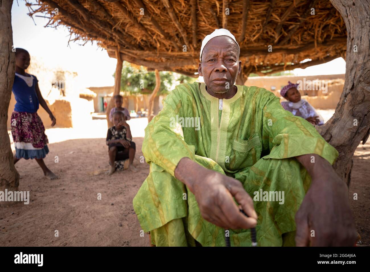 Mahammoud Traore (75) soutient une famille de 21 personnes grâce à son agriculture dans le village de Dougouninkoro, au Mali. Mais le changement climatique a affecté les tendances météorologiques ces dernières années et il n'a pas été capable de croître autant qu'il l'avait fait auparavant. Aujourd’hui, les réserves alimentaires de sa famille sont toujours à court de nourriture avant de pouvoir récolter sa nouvelle récolte. Par conséquent, il y a toujours deux mois chaque année où la famille fait l’expérience de la faim et qu’ils doivent souvent s’endetter pour acheter ou emprunter de la nourriture. Crise du Sahel 2021 ; Barouéli cercle, Mali. 22 févr. 2021. Photo de Jake Lyell. Banque D'Images