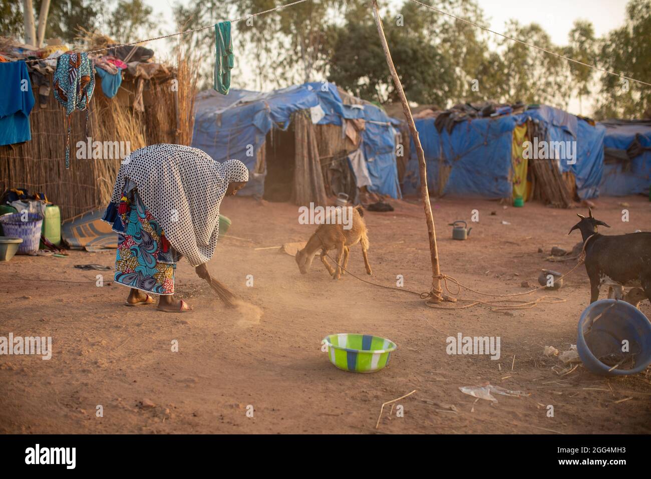 Le camp de Senou se trouve à la limite sud de Bamako, la capitale du Mali. C'est l'un des huit camps informels autour de la ville et, en soi, il abrite 223 familles et un peu plus de 1 000 personnes déplacées. Les familles qui vivent ici ont fui la violence et l'insurrection dans le nord et le centre du pays. Parce que la plupart d'entre eux n'ont pas de moyens de revenu ou de source régulière de nourriture, la faim est un défi quotidien et la malnutrition de sa population reste endémique. Ici, Fatima Bolly (33) balaie la région à l’extérieur du refuge de sa famille tôt le matin. Banque D'Images