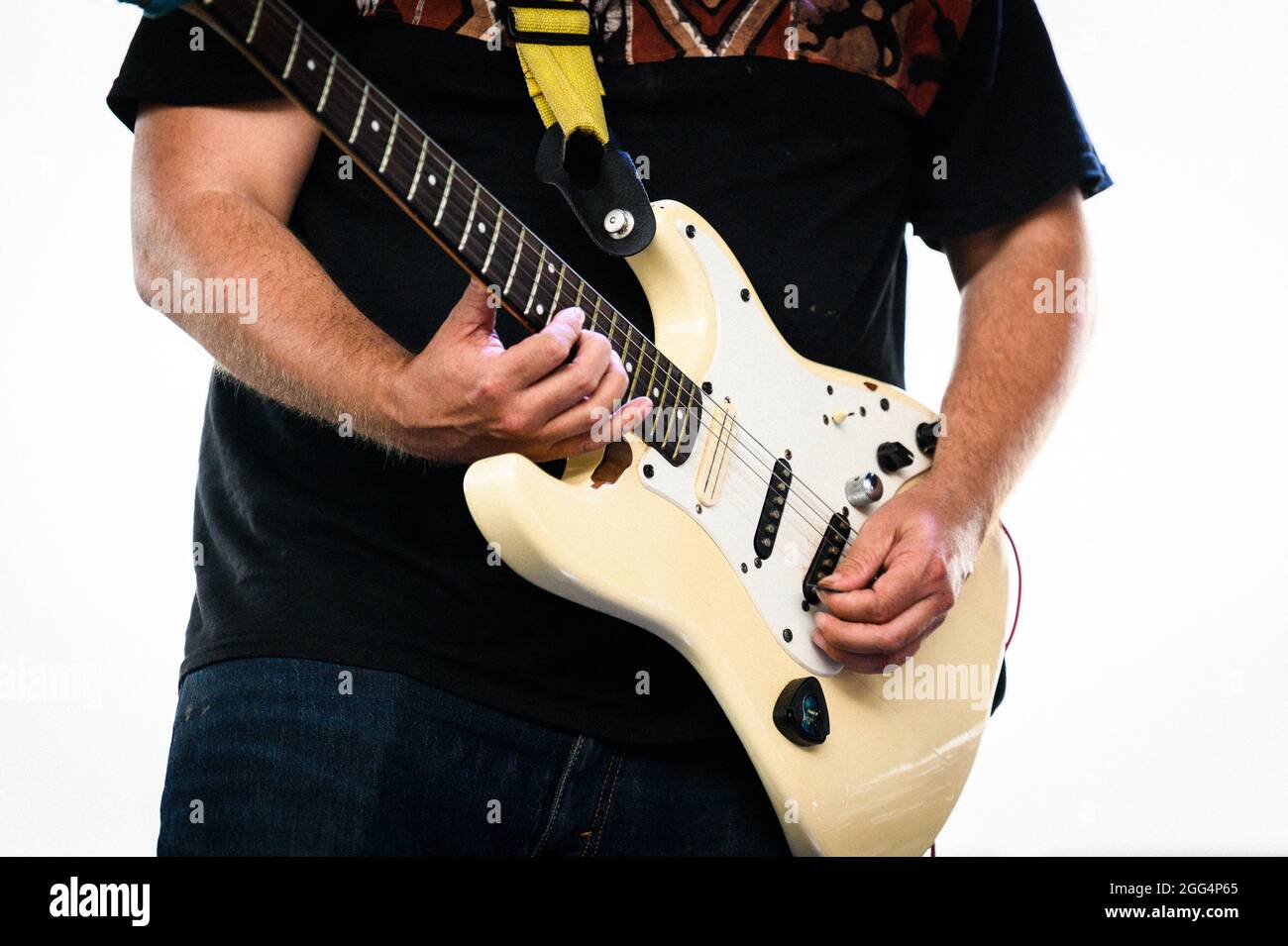 Un musicien joue le cou sur une guitare électrique blanche Fender Stratocaster gaucher. Banque D'Images