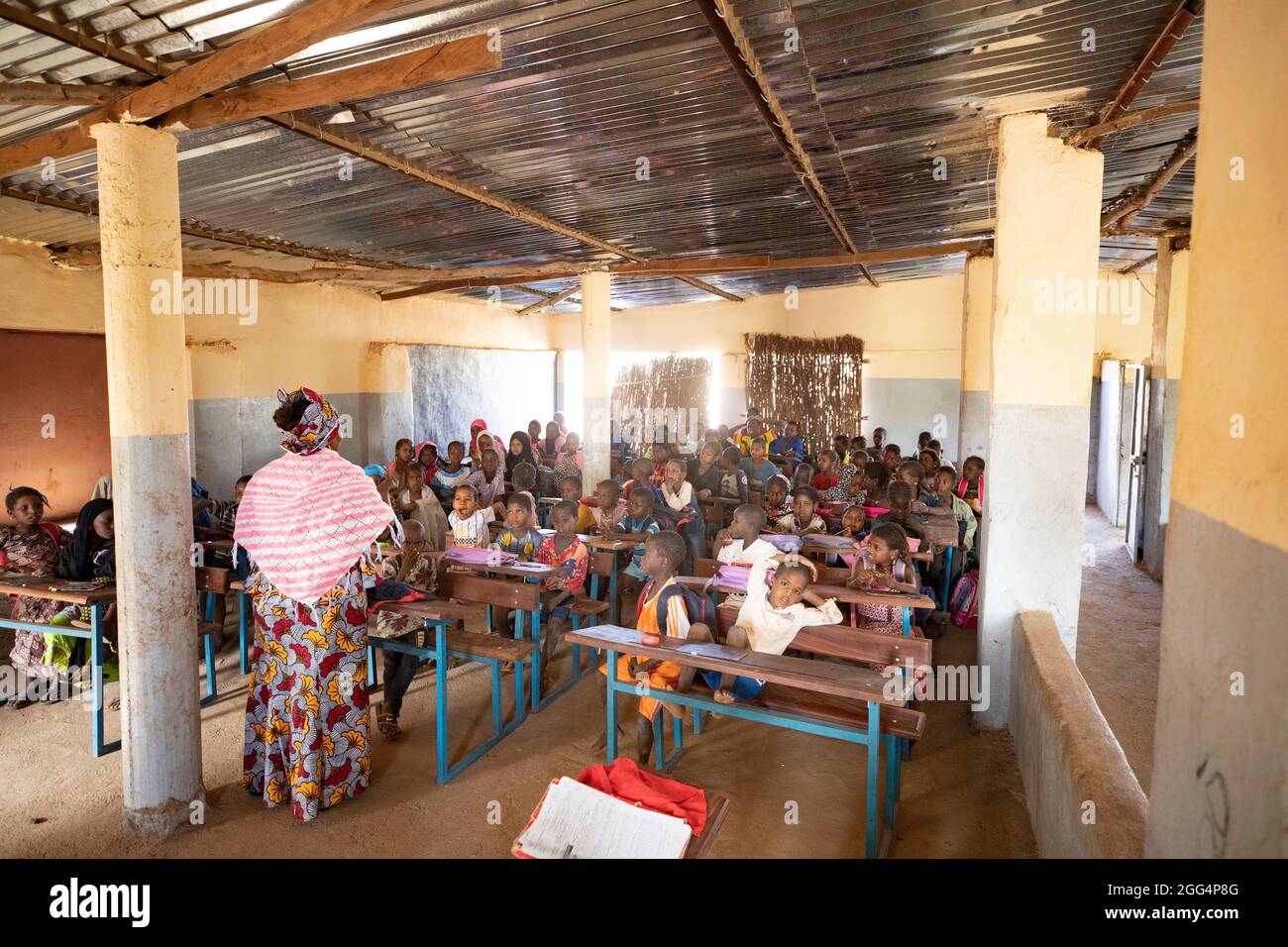 Le camp de Senou se trouve à la limite sud de Bamako, la capitale du Mali. C'est l'un des huit camps informels autour de la ville et, en soi, il abrite 223 familles et un peu plus de 1 000 personnes déplacées. Les familles qui vivent ici ont fui la violence et l'insurrection dans le nord et le centre du pays. Parce que la plupart d'entre eux n'ont pas de moyens de revenu ou de source régulière de nourriture, la faim est un défi quotidien et la malnutrition de sa population reste endémique. Ici, les enfants apprennent dans la seule école primaire du camp, enseignée par Mme Asmatou Coulibably. Banque D'Images