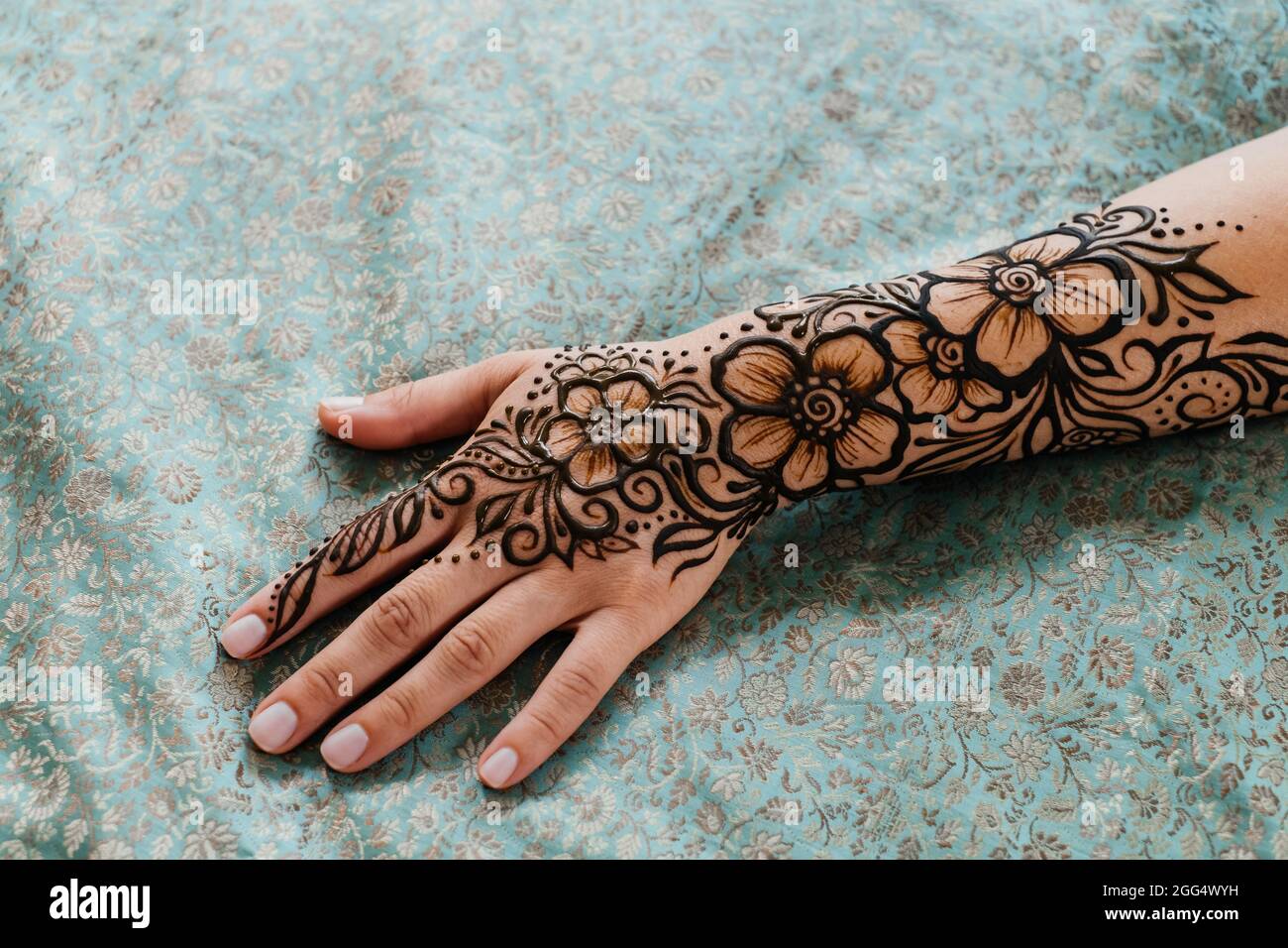 Vue de dessus art henné tatouage sur les mains des femmes. Maître artiste dessin arabe mehndi pour la mariée avant le mariage. Gros plan, vue de dessus. Motif fleuri. Cône Banque D'Images