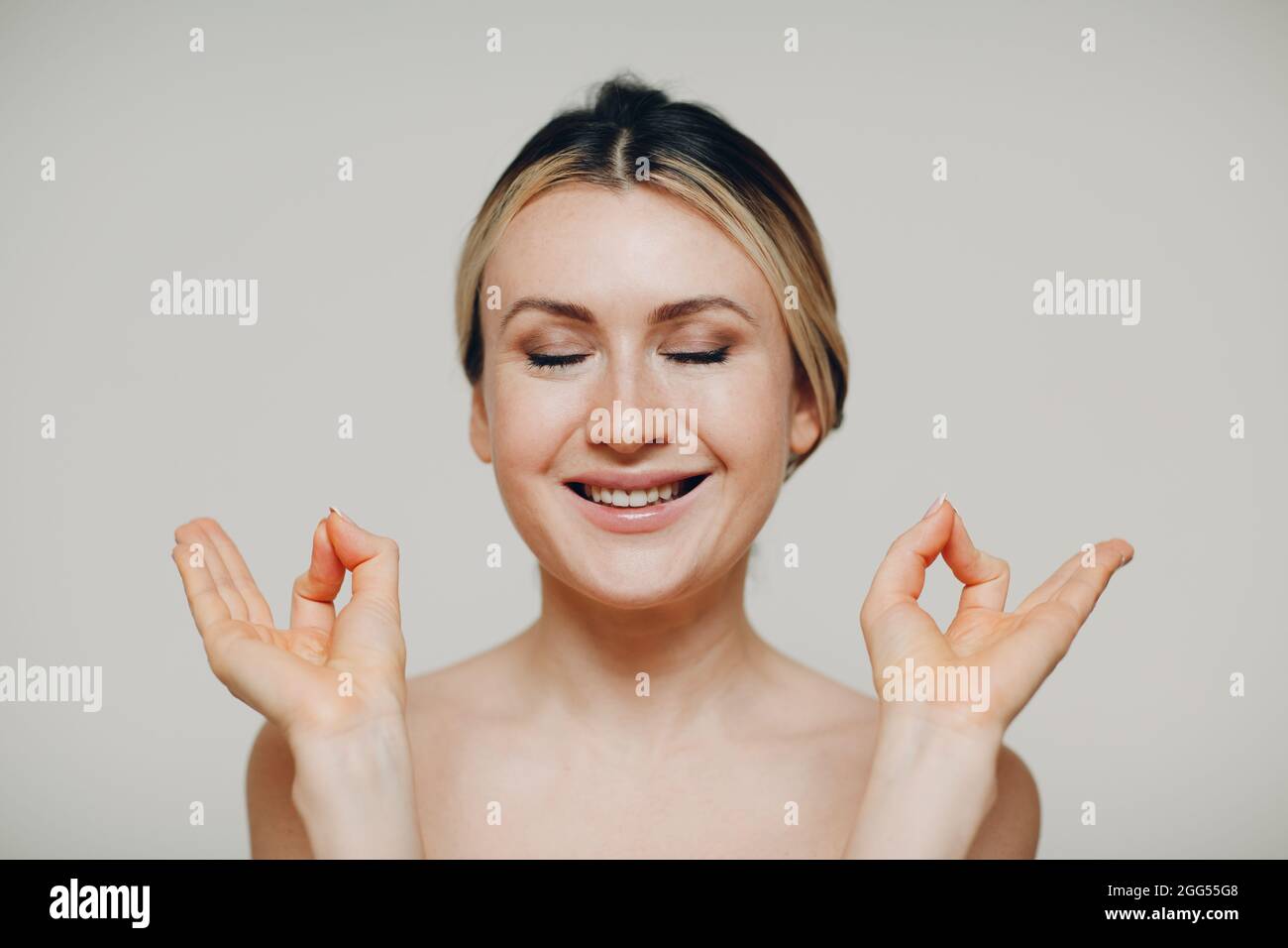 Paix intérieure et yoga, zen, concept de méditation. Jeune femme adulte souriante pratiquant le yoga et montrer le bon signe mudra avec les deux mains Banque D'Images