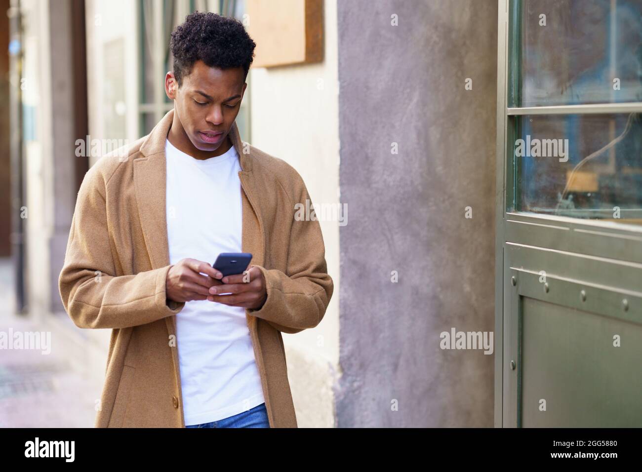 Jeune homme noir utilisant son smartphone à l'extérieur. Banque D'Images