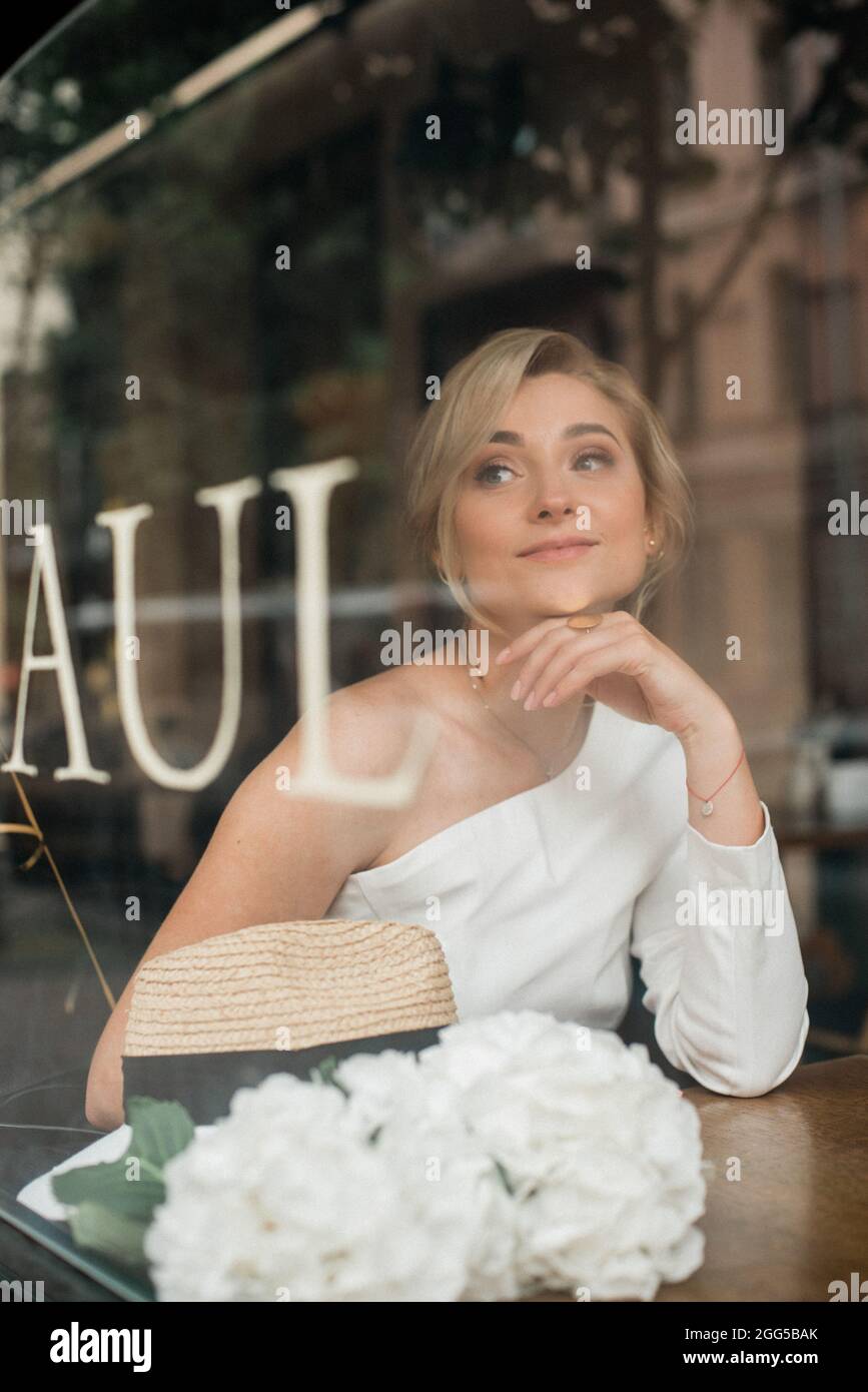 Un concept bien pensé. Belle femme élégante dans un café, regarde à travers le verre de fenêtre. Mise au point sélective douce. Banque D'Images