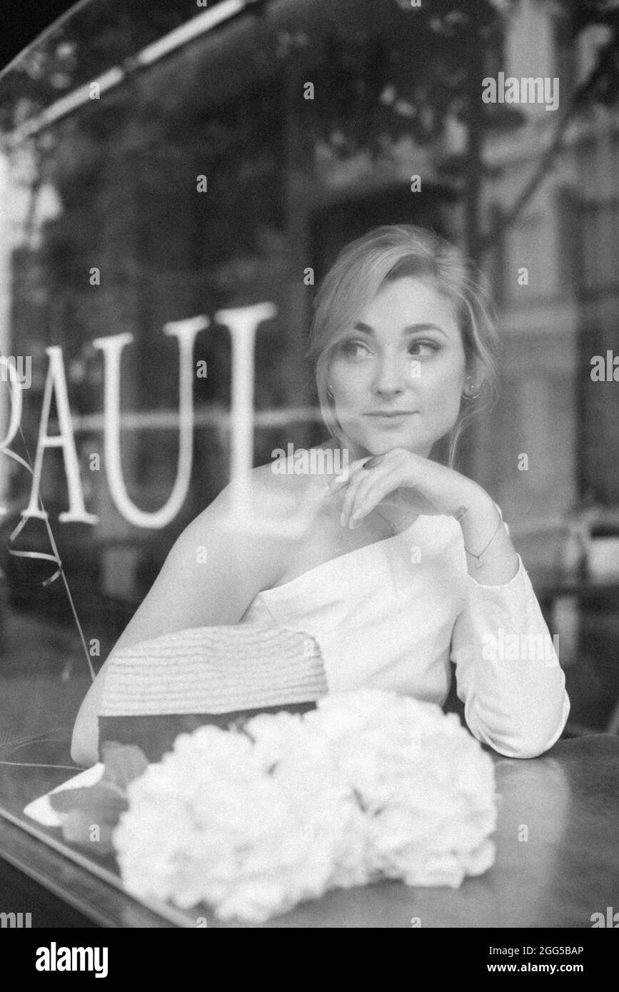 Un concept bien pensé. Belle femme élégante dans un café, regarde à travers le verre de fenêtre. Mise au point sélective douce. Banque D'Images