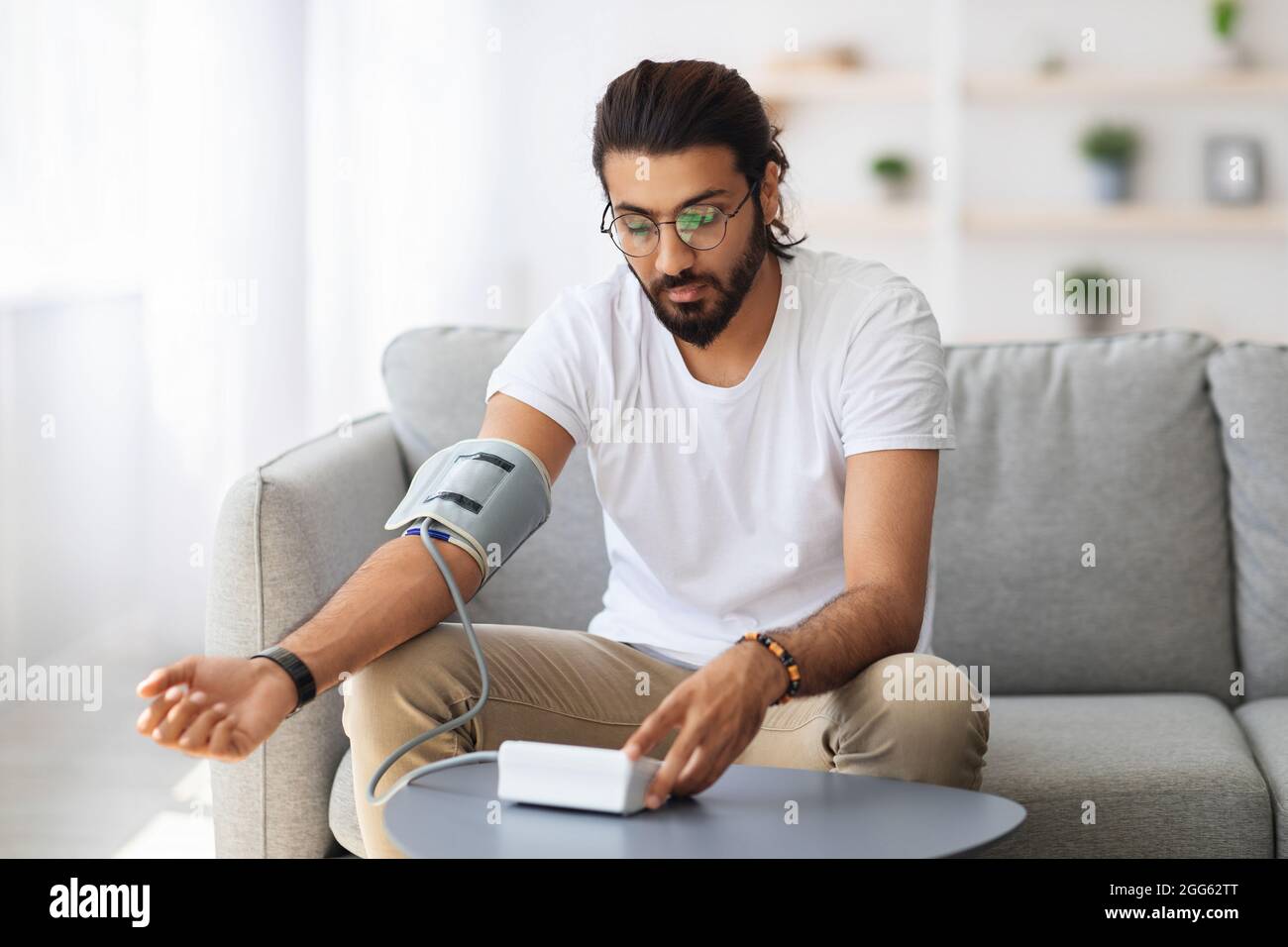 Millenny à cheveux longs vérifiant la tension artérielle, en utilisant le tonomètre Banque D'Images