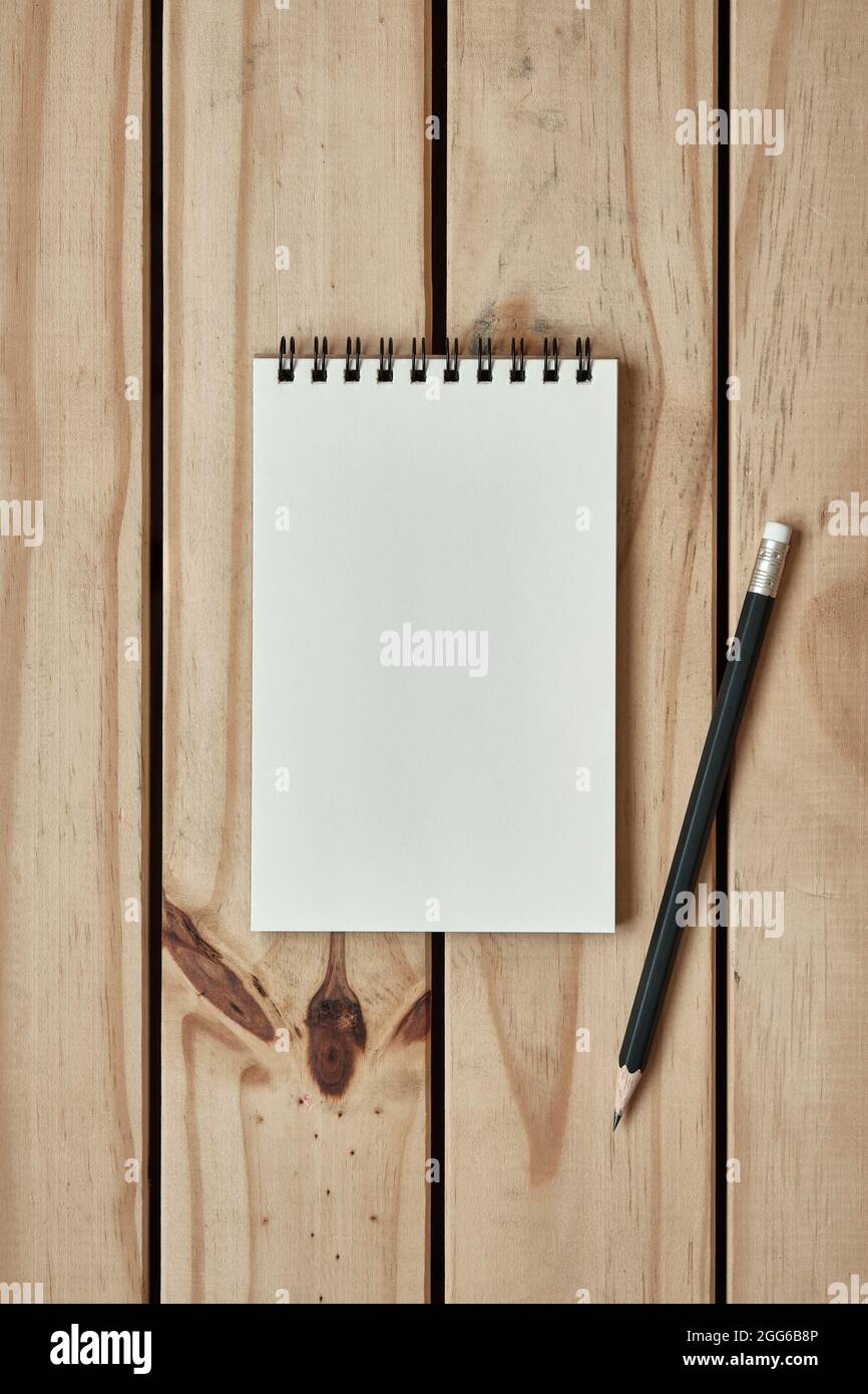 Vue de dessus de la table, bloc-notes vierge ouvert sur un bureau en bois avec crayon noir, espace de copie de la pose à plat pour le texte. Banque D'Images