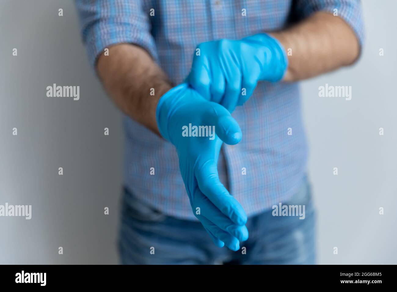 Homme portant des gants en latex de caoutchouc bleu pour le travail à domicile Banque D'Images