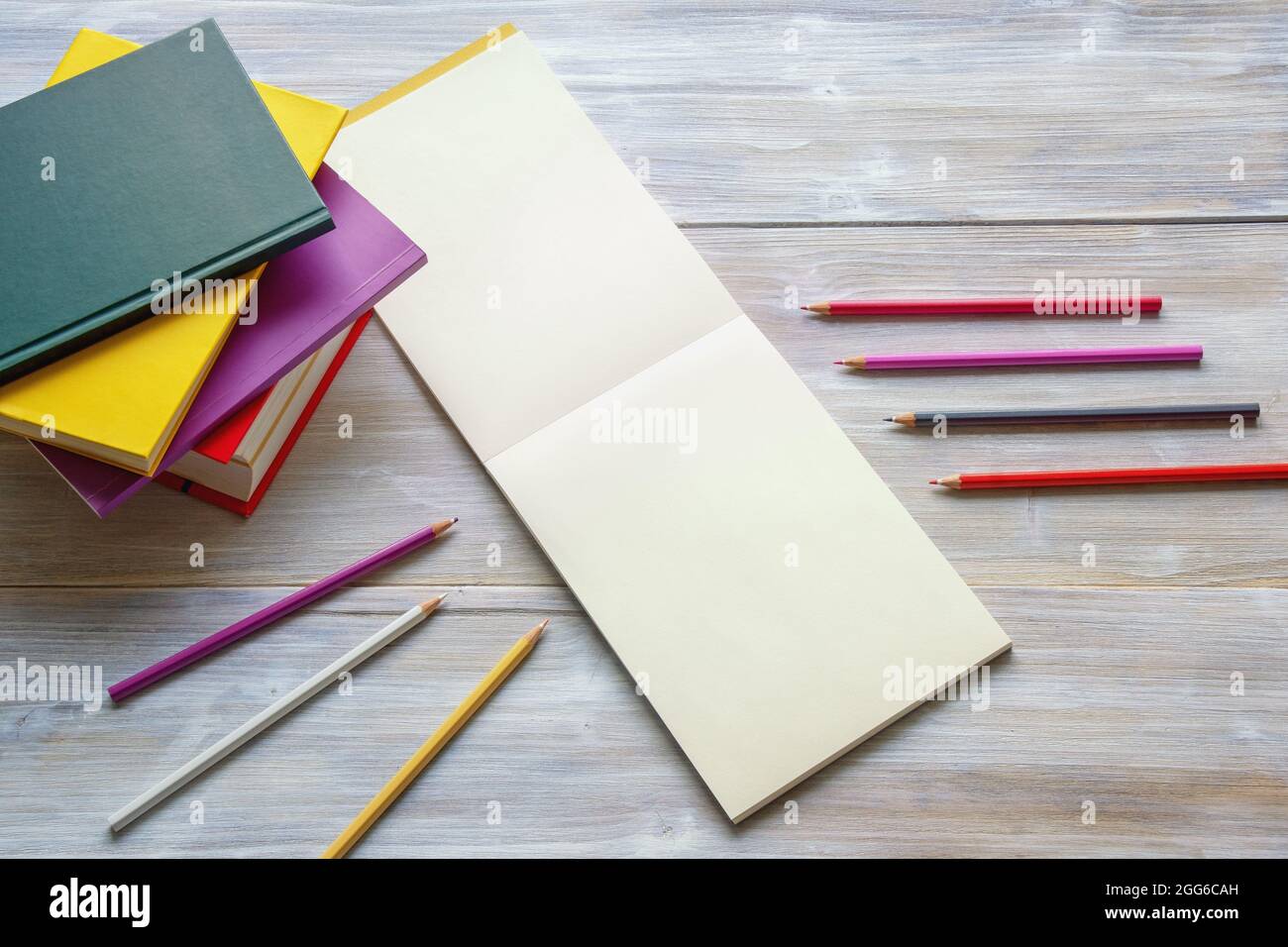 Crayons de couleur, livres et croquis ouverts sur table rustique. Espace libre pour le texte ou l'image Banque D'Images
