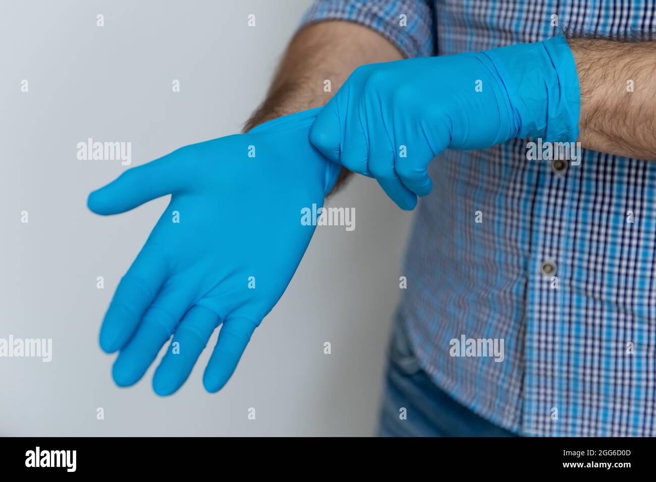 Mains de l'homme portant des gants de protection bleus en caoutchouc Banque D'Images