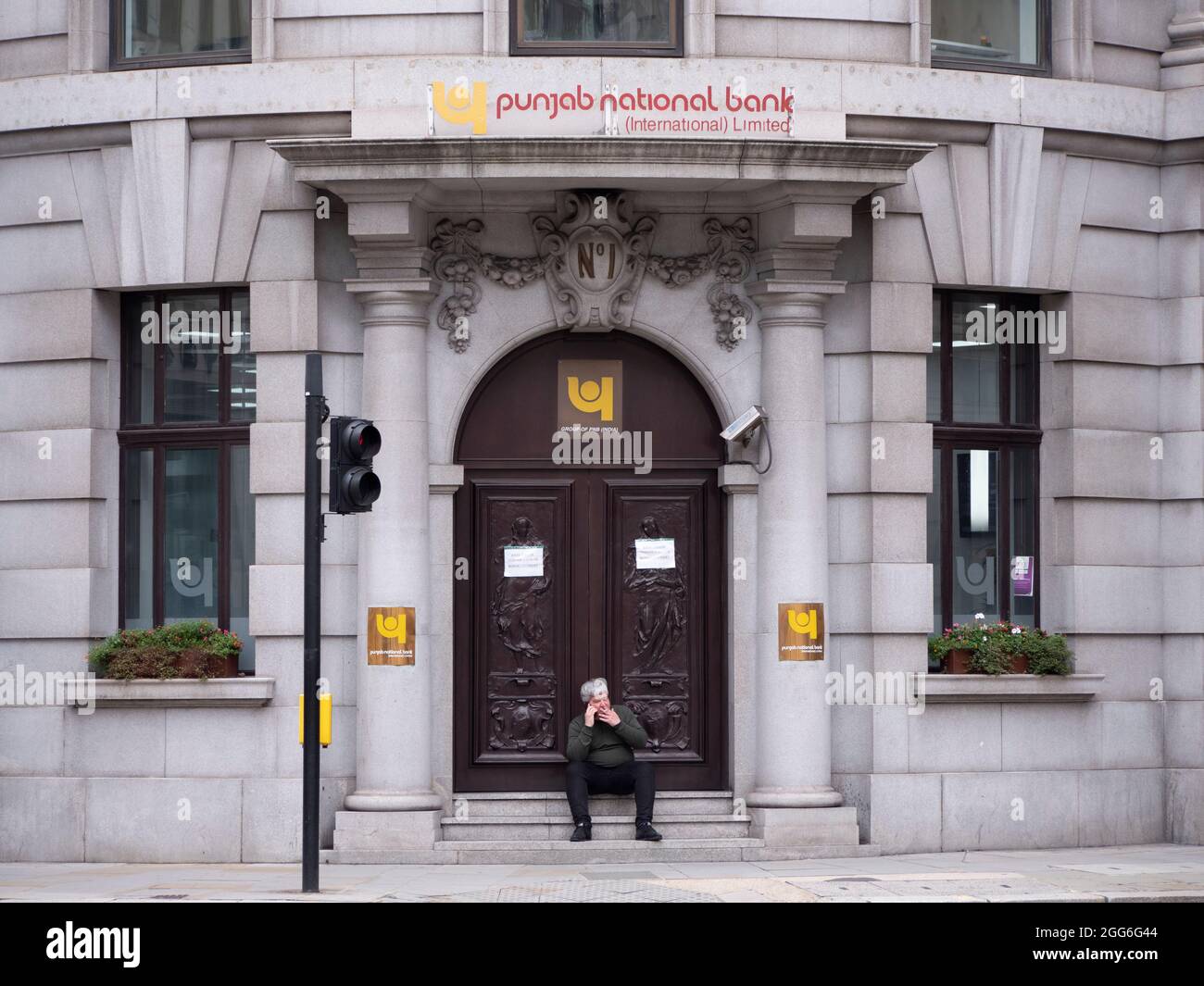 Homme assis sur les marches de la banque nationale du Punjab dans la ville de Londres, Royaume-Uni Banque D'Images