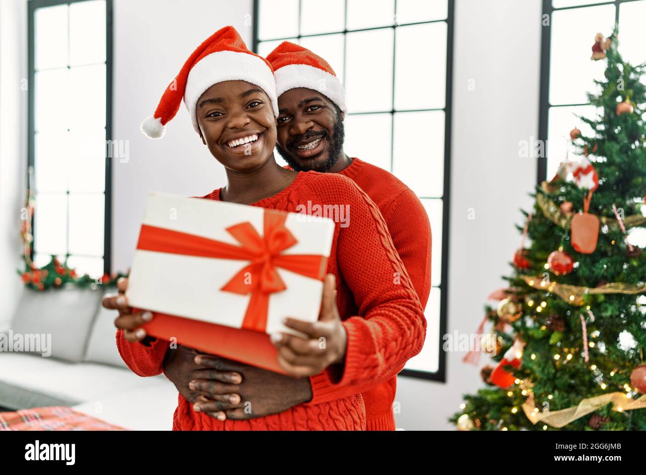 Un jeune couple afro-américain souriant et embrassant un cadeau de noël à  la maison Photo Stock - Alamy