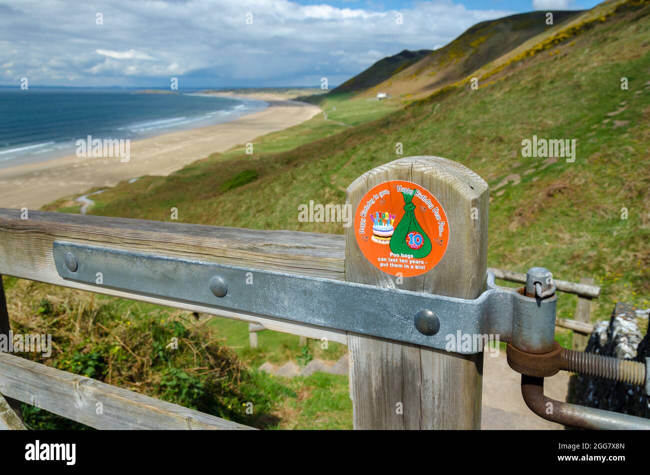 Magnifique baie de Rhossili avec panneau d'avertissement de poo de chien affiché en évidence sur UNE porte dans le premier plan Banque D'Images