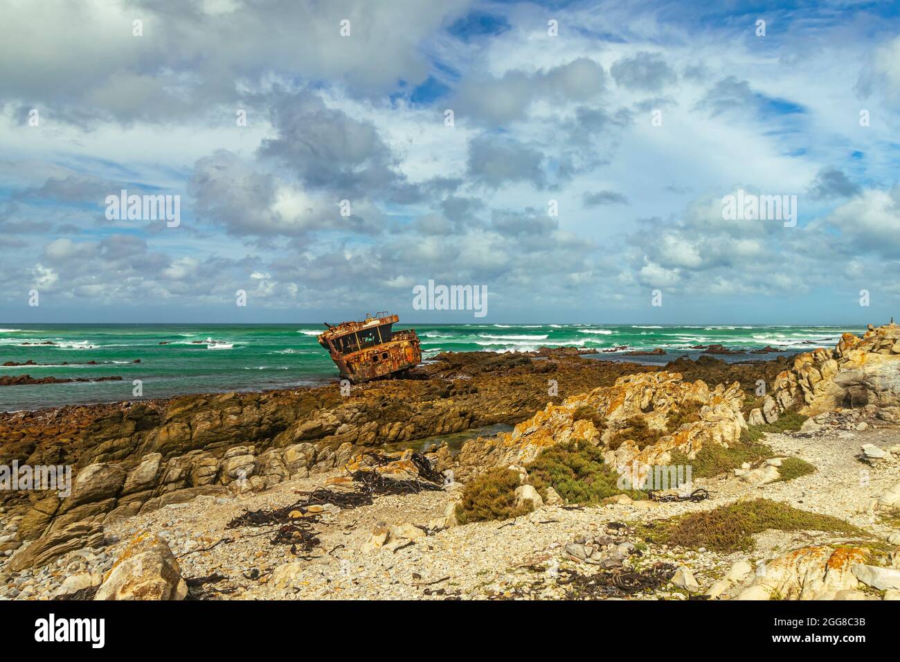 Côte rocheuse robuste avec naufrage rouillé de Meisho Maru No.38 à Cape Agulhas en Afrique du Sud qui est le point le plus au sud du continent africain. Banque D'Images