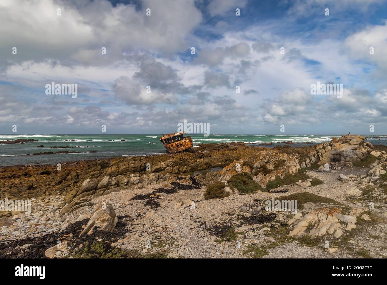 Côte rocheuse robuste avec naufrage rouillé de Meisho Maru No.38 à Cape Agulhas en Afrique du Sud qui est le point le plus au sud du continent africain. Banque D'Images