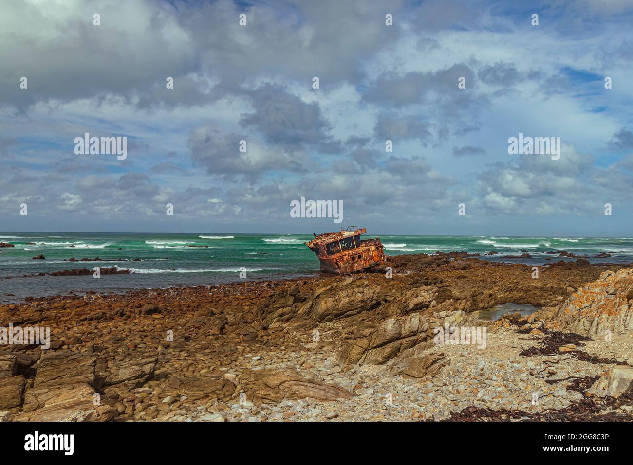 Côte rocheuse robuste avec naufrage rouillé de Meisho Maru No.38 à Cape Agulhas en Afrique du Sud qui est le point le plus au sud du continent africain. Banque D'Images