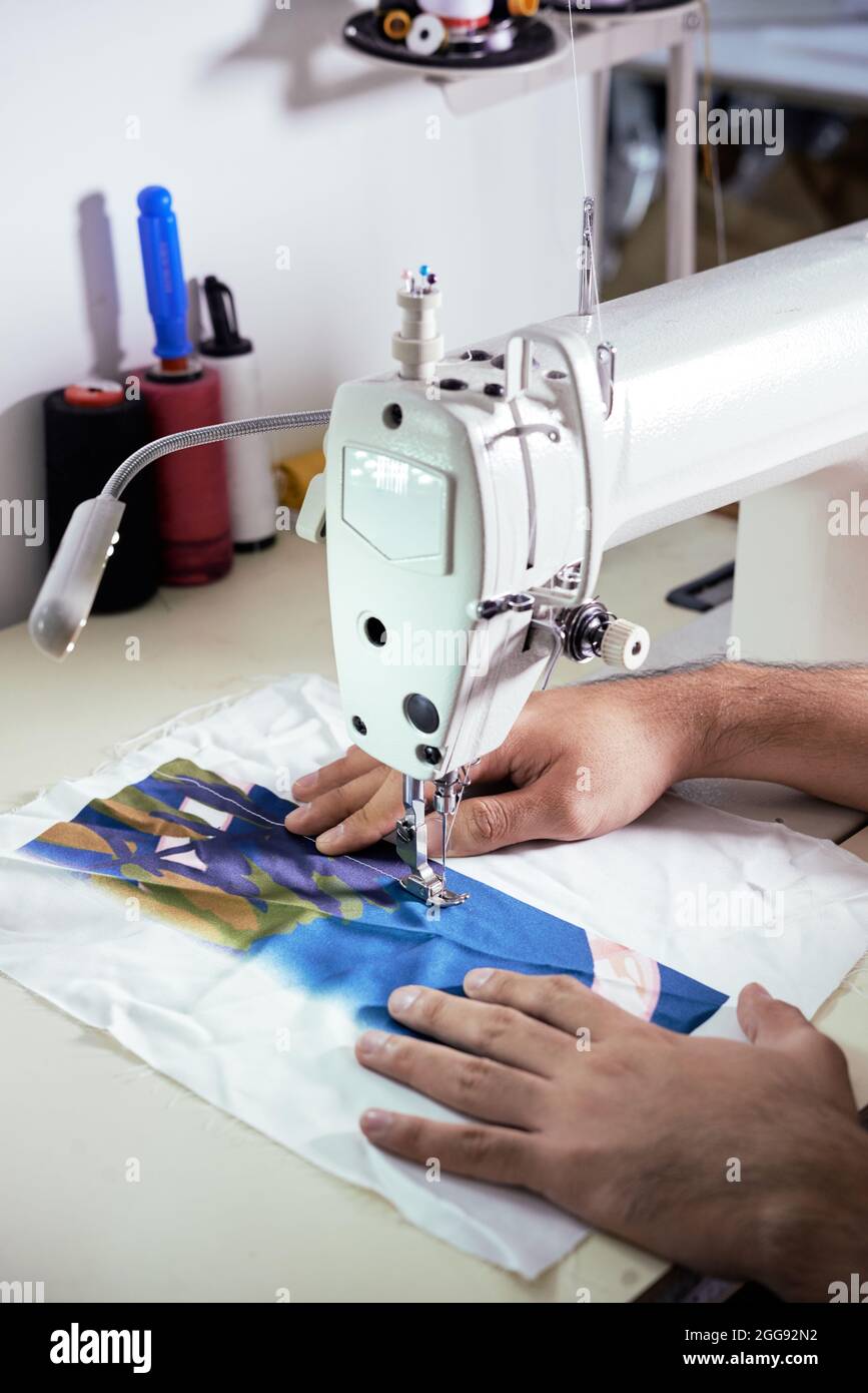 Mains de l'homme sur mesure testant le nouveau tissu de soie et de faire peu de points sur la machine à coudre Banque D'Images
