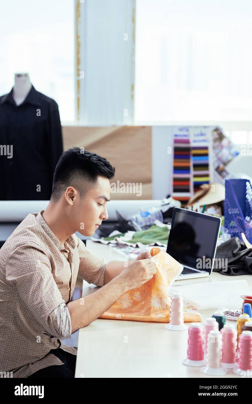 Sérieux jeune tailleur travaillant en studio, il fait un échantillon de robe pour la nouvelle collection Banque D'Images
