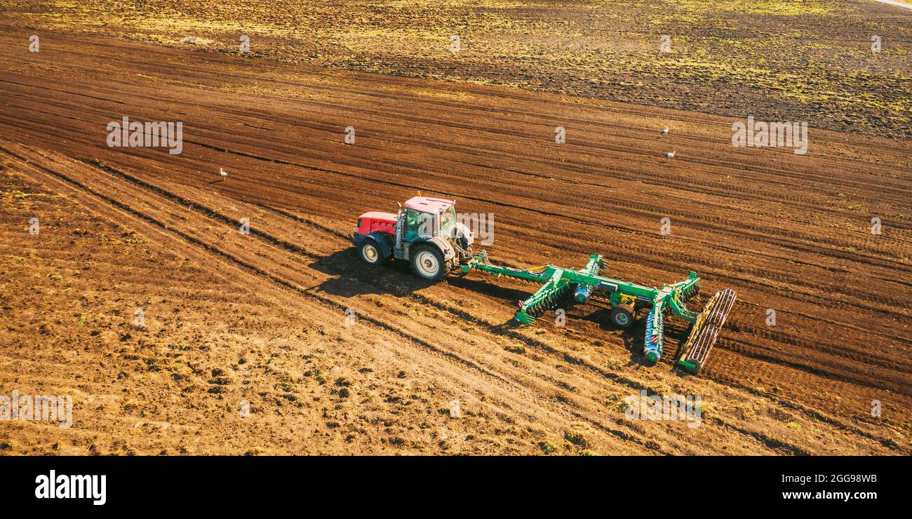 Vue aérienne. Le tracteur labourage dans le champ. Début de la saison agricole du printemps. Cultivateur tiré par UN tracteur dans un paysage rural de campagne Banque D'Images