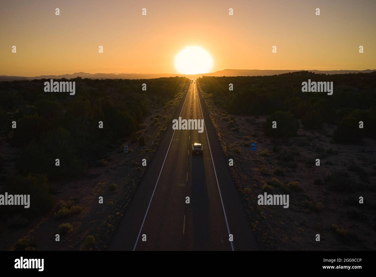 Voiture sur une autoroute allant directement au coucher du soleil à l'horizon, Utah, États-Unis Banque D'Images