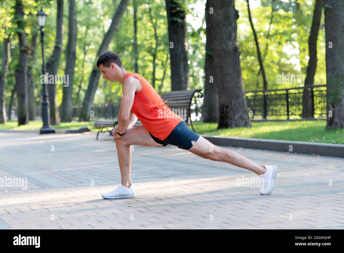 Sportsman tenir la position de fente faire une routine d'étirement pendant l'entraînement sportif en plein air dans le parc, l'échauffement Banque D'Images