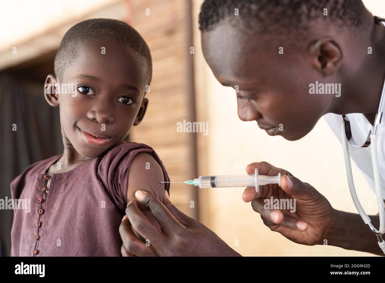 Mignon petit garçon africain noir regardant la caméra pendant la vaccination de routine; concept de prévention de maladie d'enfance Banque D'Images