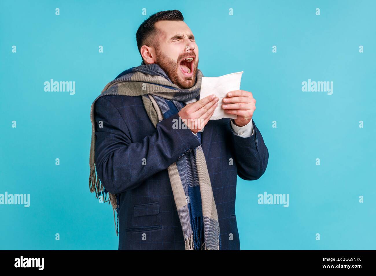 Toux ou éternuements. Homme malade enveloppé dans un foulard éternuant, toussant, se sentant mal, malade ou grippe, souffrant d'allergie ou de syndrome grippal saisonnier Banque D'Images