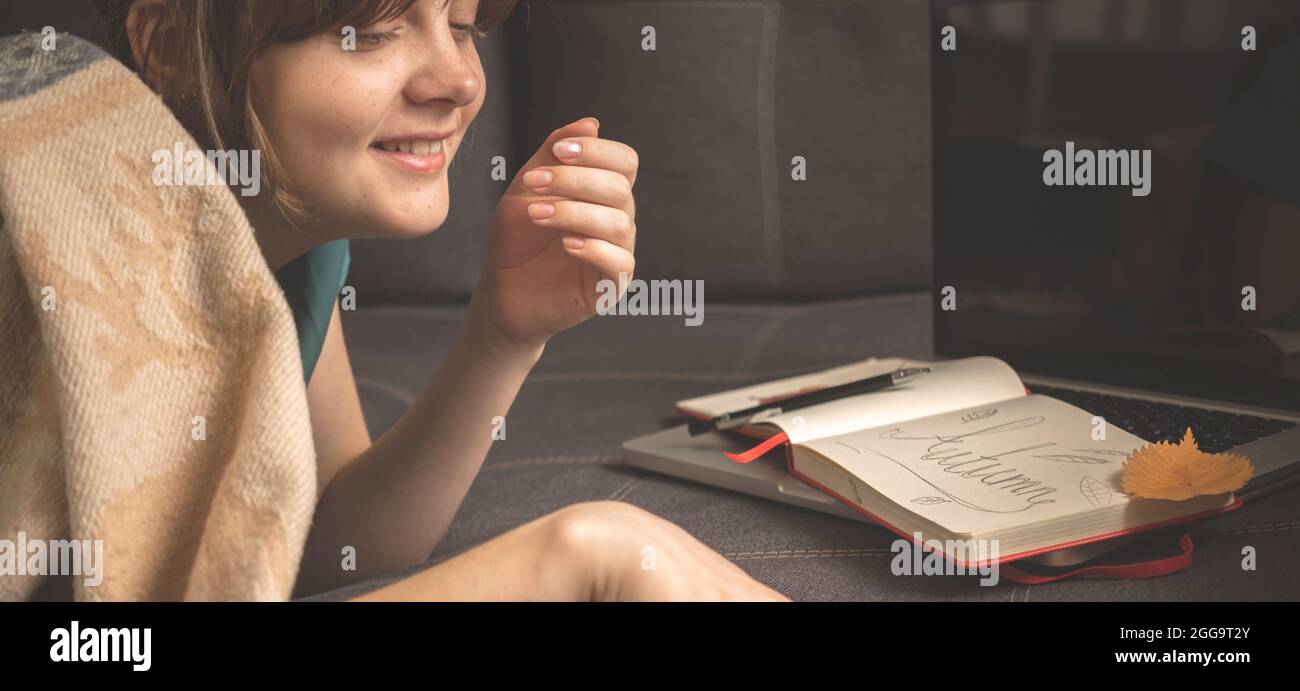 Bannière jeune fille rit tout en lisant un livre à la maison dans les jours d'automne confortables, l'arrière-plan hygge Banque D'Images