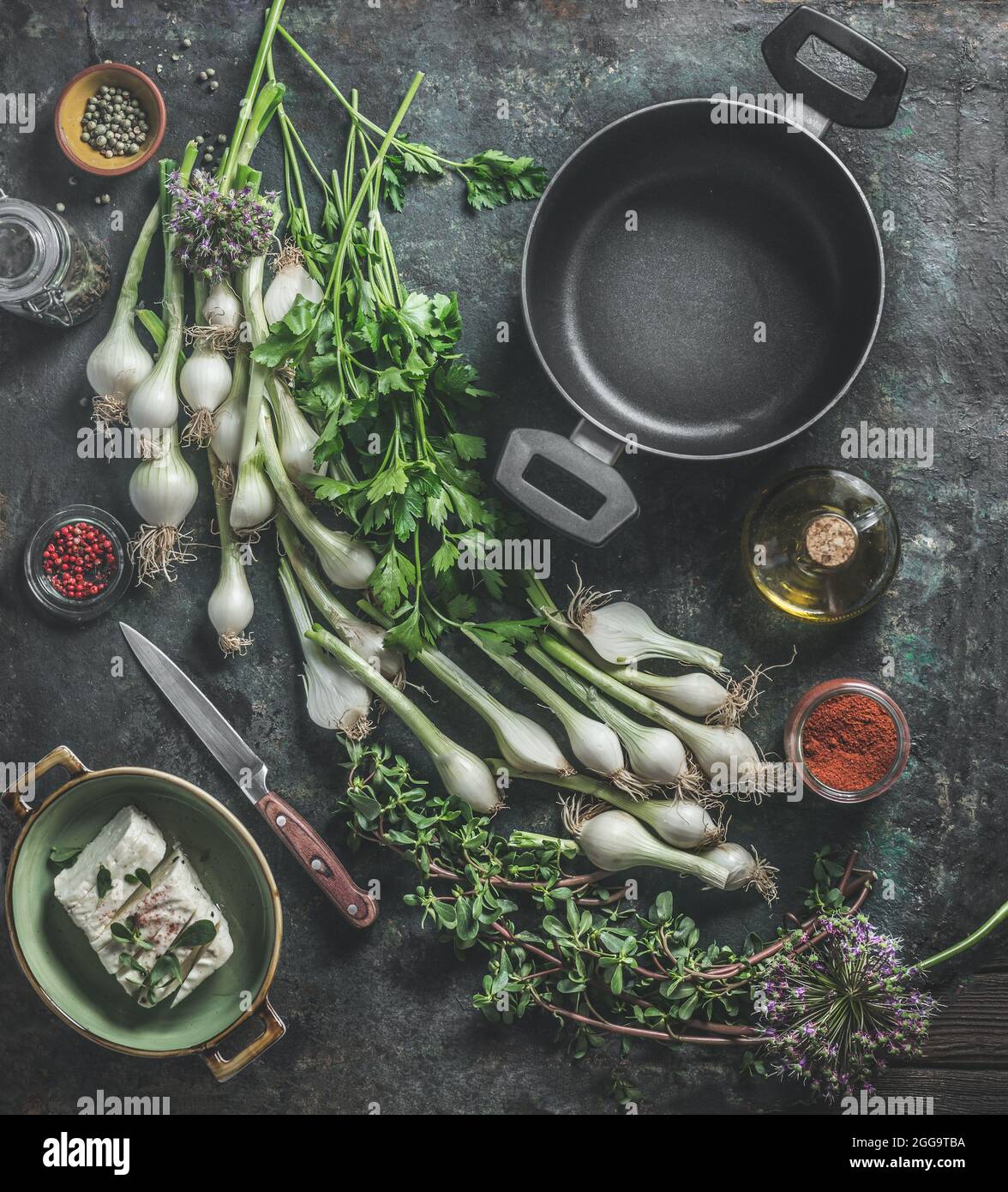 Videz la casserole noire et la variété d'herbes fraîches pour cuisiner sur une table rustique sombre avec couteau, fromages, huile d'olive et épices. Cuisine maison. Vue de dessus Banque D'Images