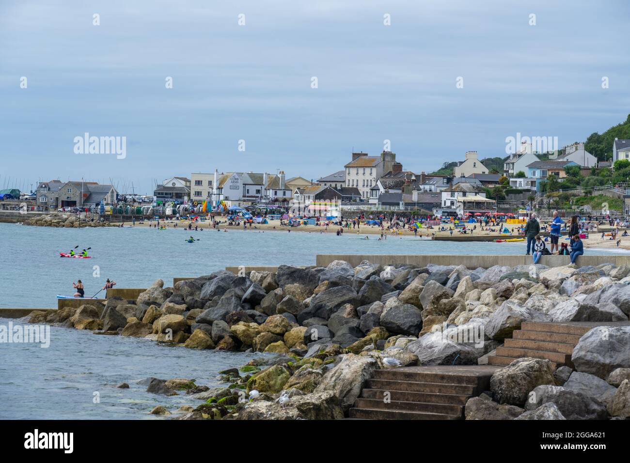 Lyme Regis, Dorset, Royaume-Uni. 30 août 2021. UK Weather: La plage à la station balnéaire de Lyme Regis était plus calme que prévu car les vacanciers et les Beach-goers ont fait le meilleur de la déception nuageux début à la banque vacances lundi. Les gens ont marché le long du front de mer tandis que d'autres se sont assis sur la plage pour attendre le soleil pour faire l'aspect occassional. Le crédit: Celia McMahon/Alamy Live News Banque D'Images