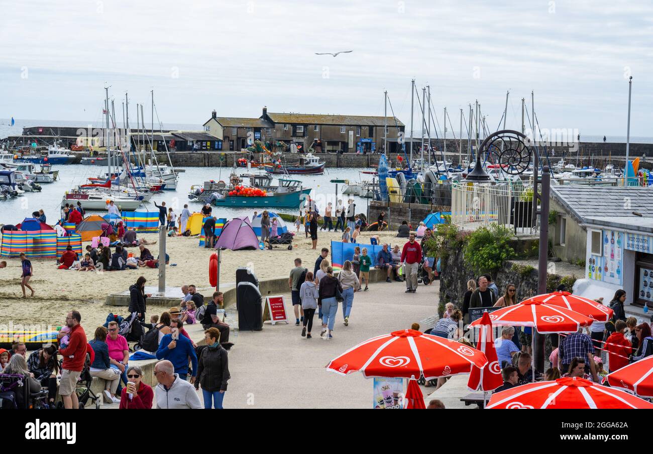 Lyme Regis, Dorset, Royaume-Uni. 30 août 2021. UK Weather: La plage à la station balnéaire de Lyme Regis était plus calme que prévu car les vacanciers et les Beach-goers ont fait le meilleur de la déception nuageux début à la banque vacances lundi. Les gens ont marché le long du front de mer tandis que d'autres se sont assis sur la plage pour attendre le soleil pour faire l'aspect occassional. Le crédit: Celia McMahon/Alamy Live News Banque D'Images