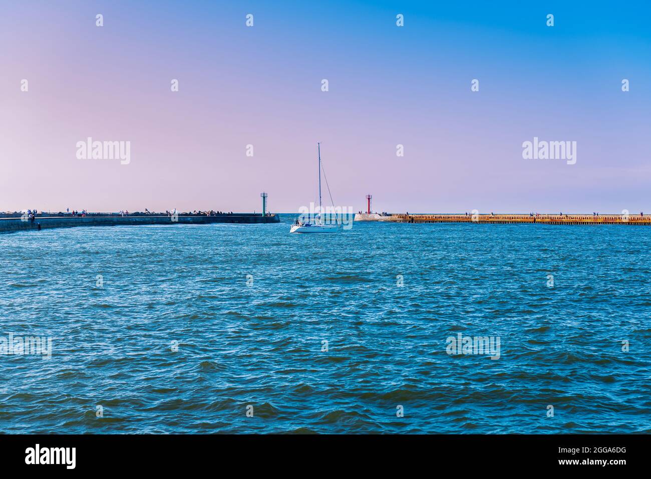 vue sur la baie dans le port, un voilier entrant dans le port par une journée ensoleillée, brise-lames en béton en arrière-plan Banque D'Images