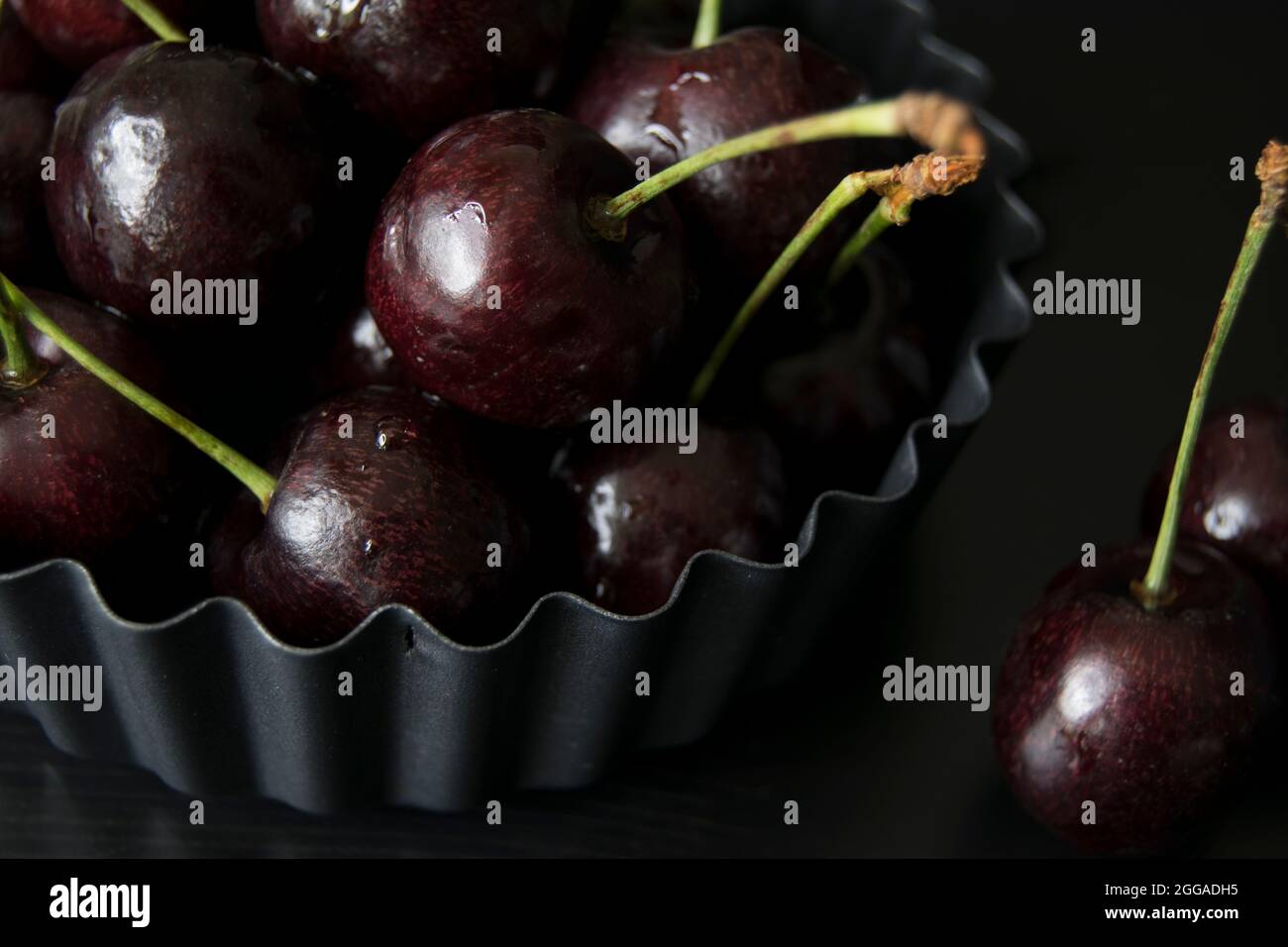Cerises noires juteuses dans un plat de flan cannelé Banque D'Images