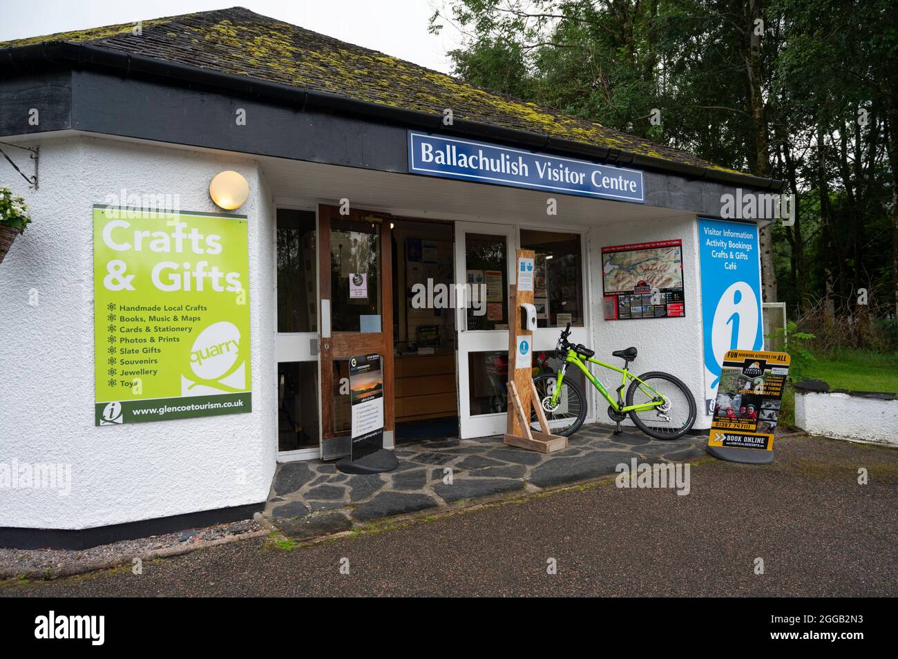 Extérieur du centre d'accueil de Ballachulish avec des panneaux indiquant les informations sur les visiteurs, le café, la boutique de cadeaux et les activités. Vélo laissé à l'extérieur, personne. Banque D'Images
