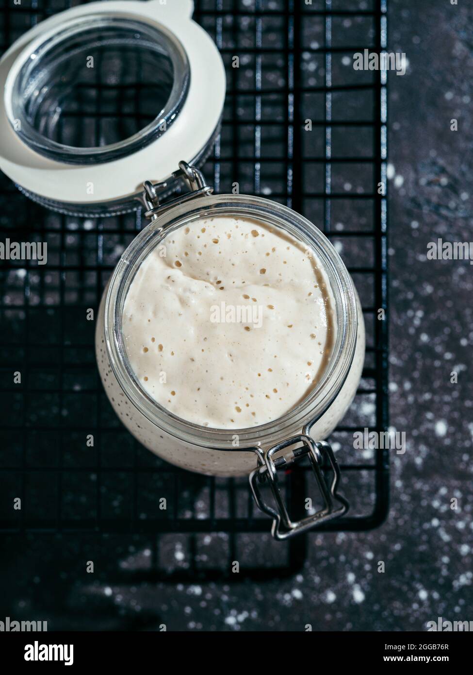 Démarreur de levain de blé. Bol en verre avec entrée de levain sur fond sombre, espace de copie. Verticale. Banque D'Images
