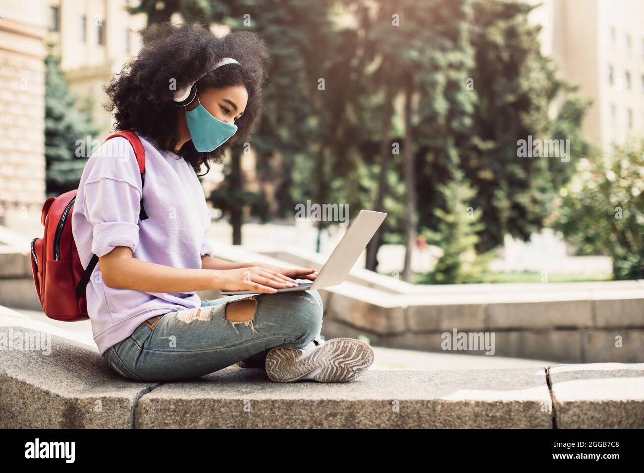 African Student Girl Learning Online en utilisant le masque de port d'ordinateur portable à l'extérieur Banque D'Images