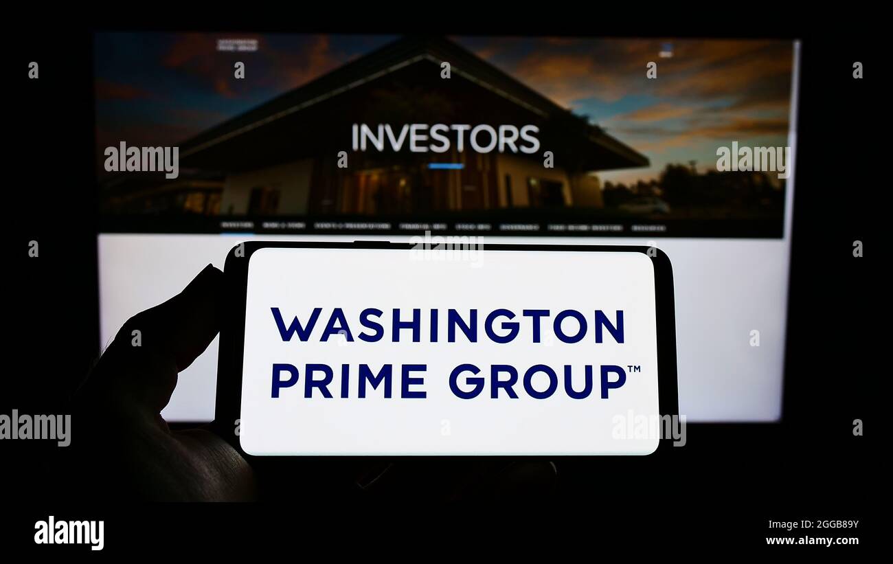 Personne tenant un smartphone avec le logo de la société immobilière américaine Washington Prime Group Inc. À l'écran devant le site Web. Mise au point sur l'affichage du téléphone. Banque D'Images