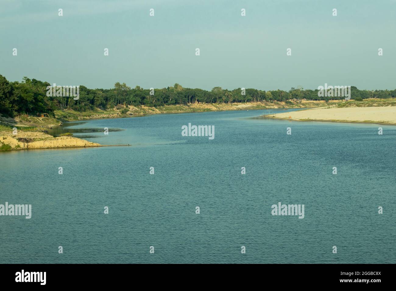 La petite rivière près du village et la rive à feuilles persistantes avec de l'eau bleu océan Banque D'Images