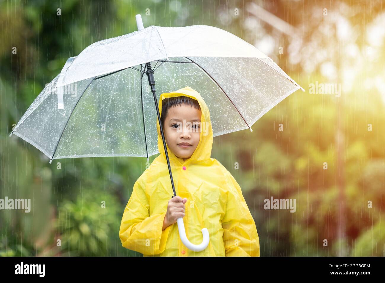 Portrait d'un enfant asiatique tenant un parapluie avec des gouttes de  pluie. Joyeux petit enfant asiatique ayant du plaisir à jouer avec la pluie  dans la lumière du soleil du soir Photo