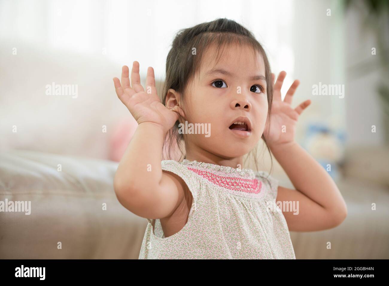 Adorabl petite fille faisant le visage drôle en jouant à la maison Banque D'Images