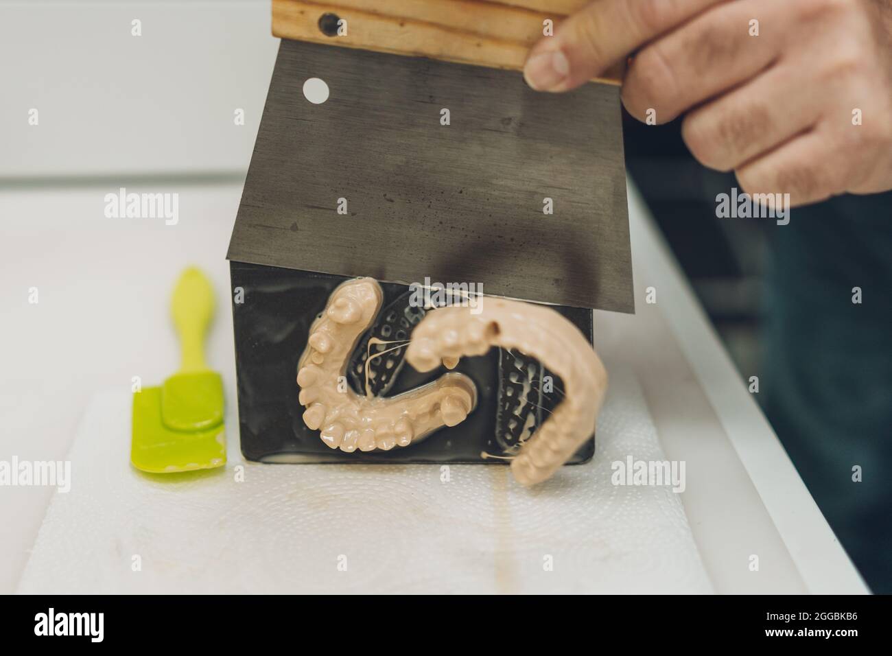 Vue rapprochée des mains d'un homme qui détache un moule fabriqué avec une imprimante 3D de la base de l'imprimante Banque D'Images