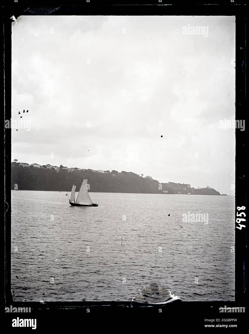 États-Unis Fish Commission Steamer « Albatross » Circumnavigation of South America, 1888. Vue sur la côte depuis un bateau avec des pêcheurs locaux sur un voilier, le détroit de Magellan. Banque D'Images