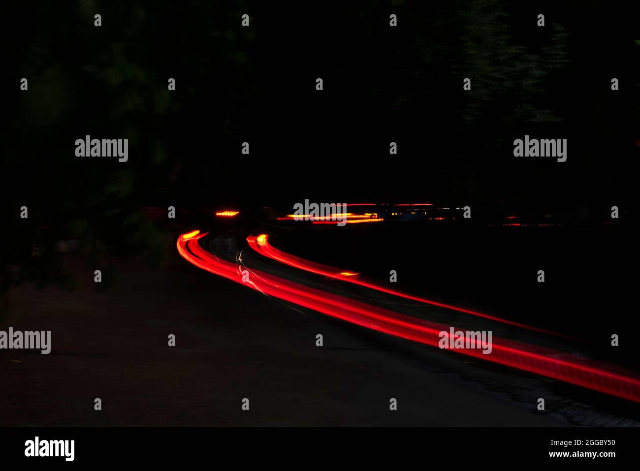 Car Light s'allume sur une rue de la ville dans une nuit noire sombre. La photo est prise avec un long exposant. Banque D'Images