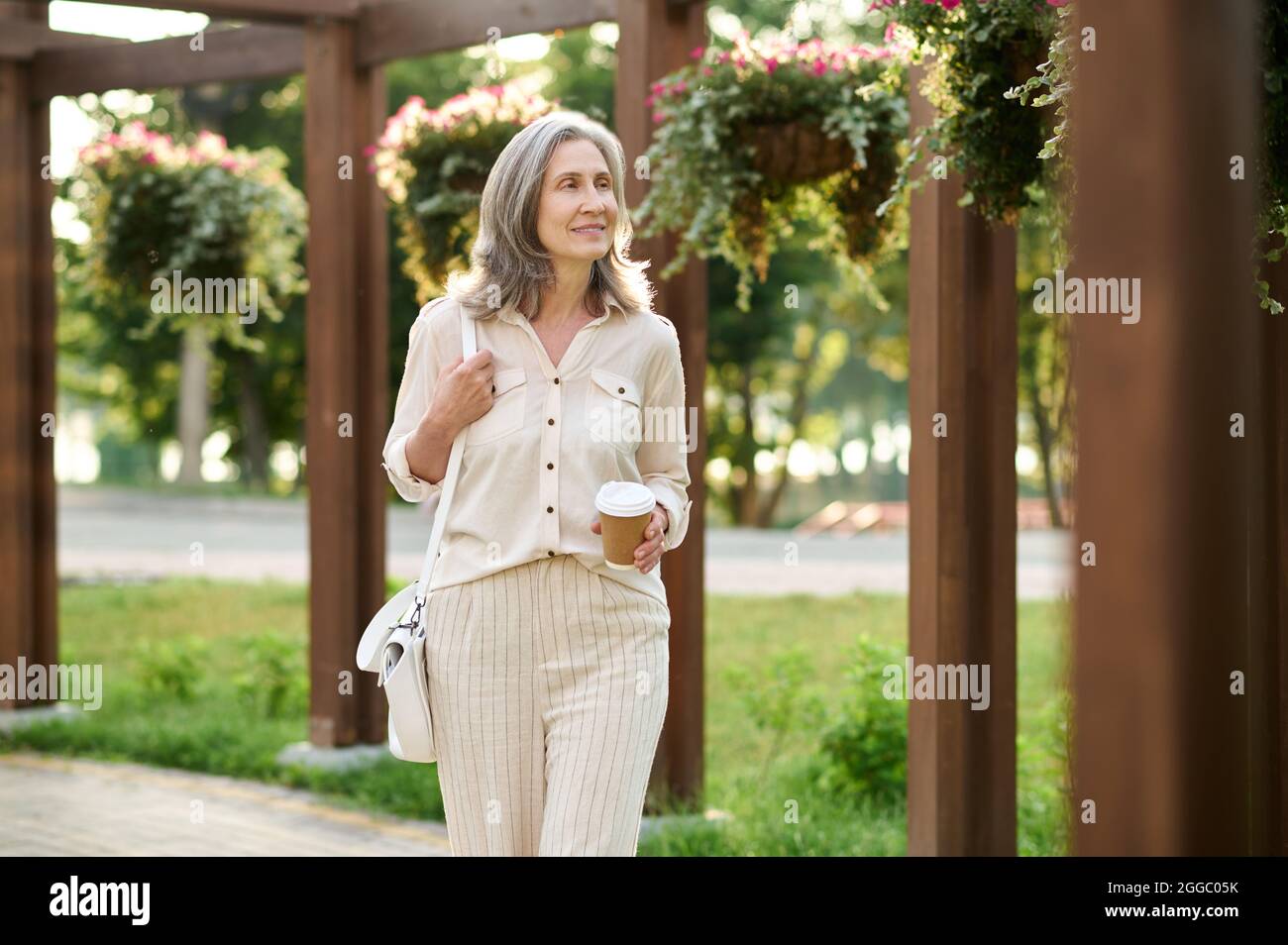 Femme avec café marchant dans le parc vert Banque D'Images